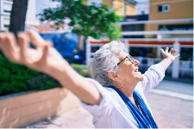 Senhora sorrindo de braços abertos, sentindo liberdade de movimento